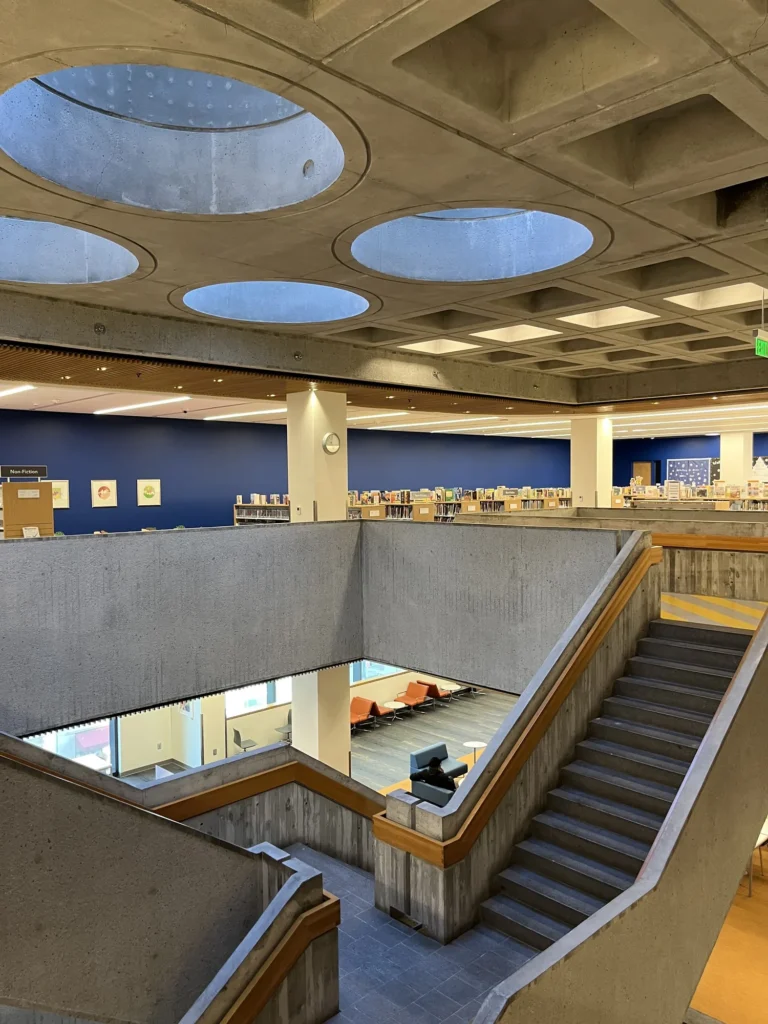Board-formed concrete stair, wooden handrail, and circular skylights at the Atlanta Central Library