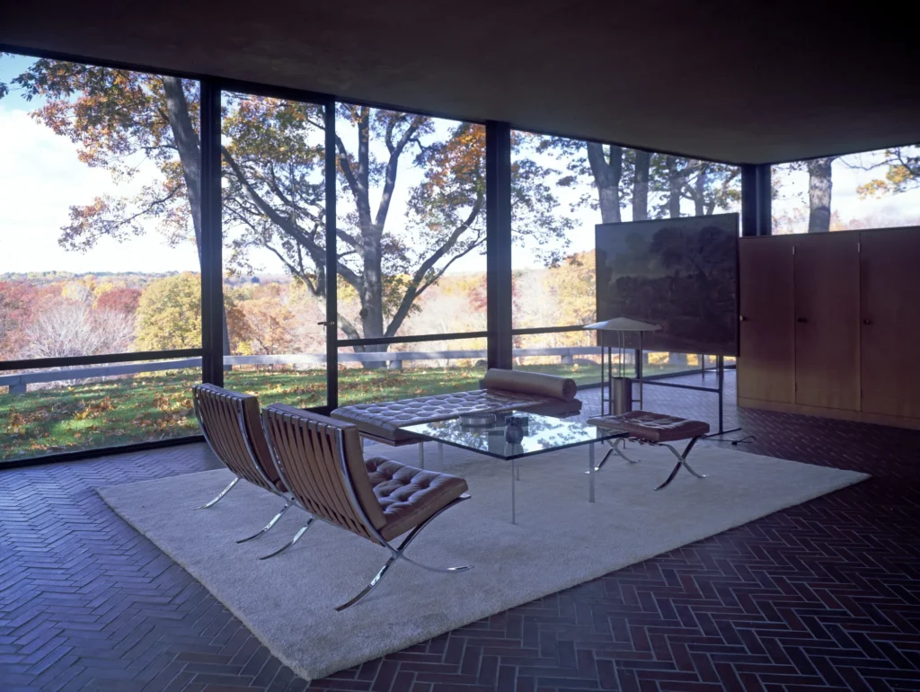 Fauteuils et table basse en verre réunis sur un tapis dans le séjour de la Glass House